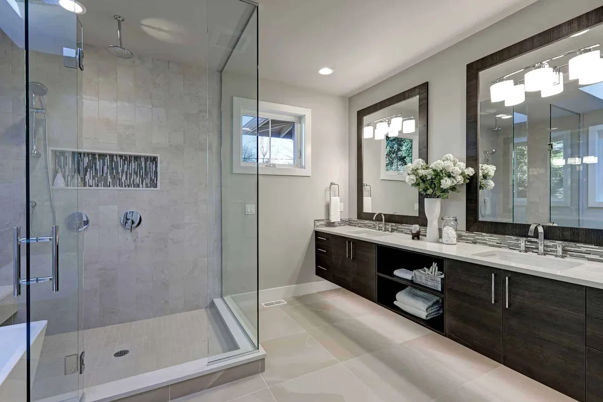 Frameless glass shower enclosure beside a double-vanity bathroom with large mirrors