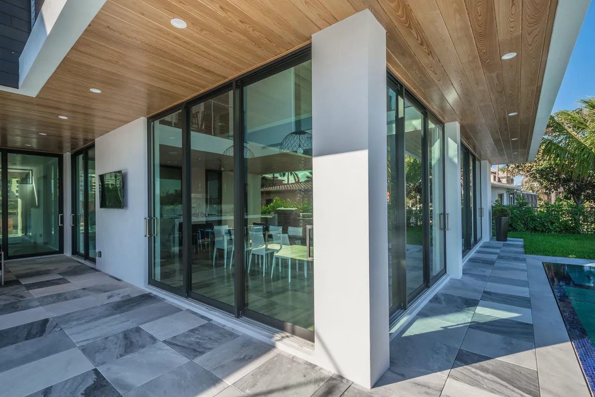 Large black-framed sliding glass doors opening a covered patio to the interior